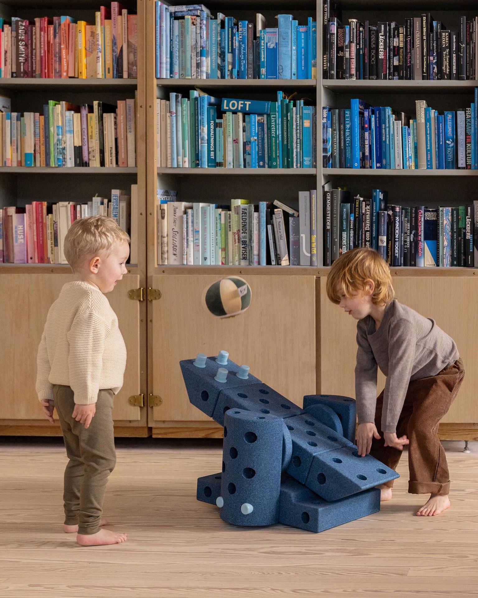 Twee jongens spelen met een bal dmv hun zelf gebouwde constructie uit Modu bouwstukken. 